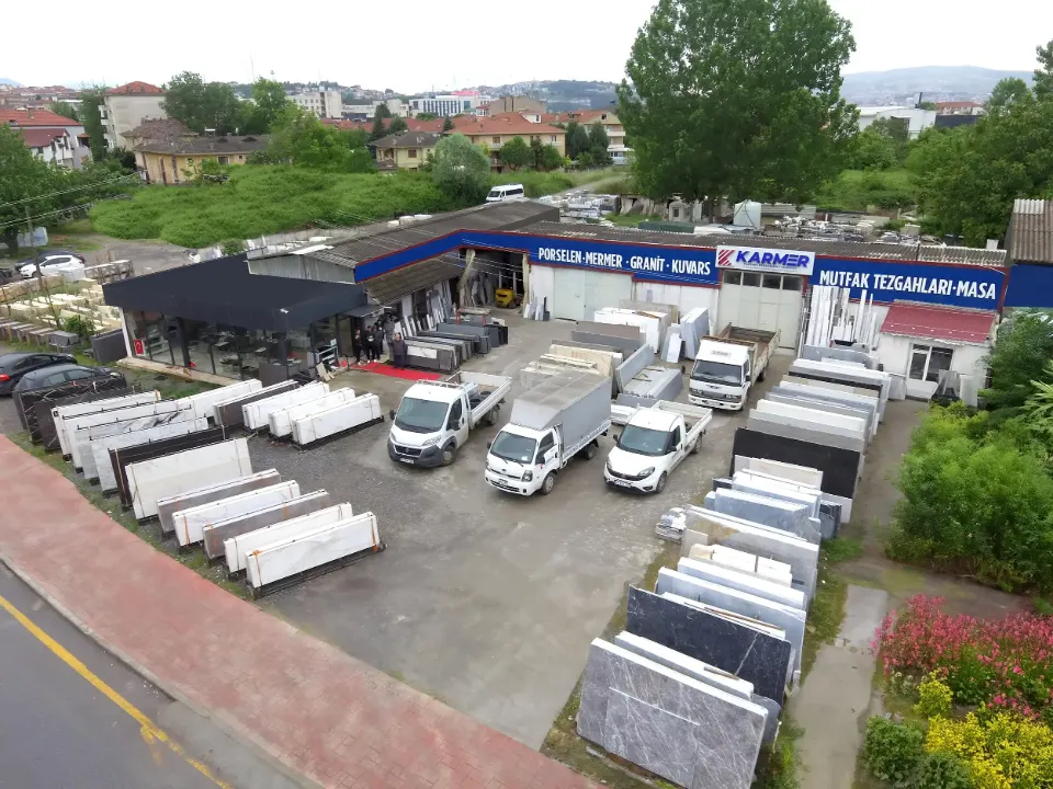 Karmer Granit Mermer tesisinin havadan görünümü: porselen, mermer, granit ve kuvars plakalar, teslimat araçları ve mağaza